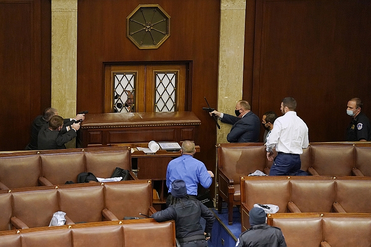 Guns are drawn in the House Chamber on January 6th as rioters attempt to break in.