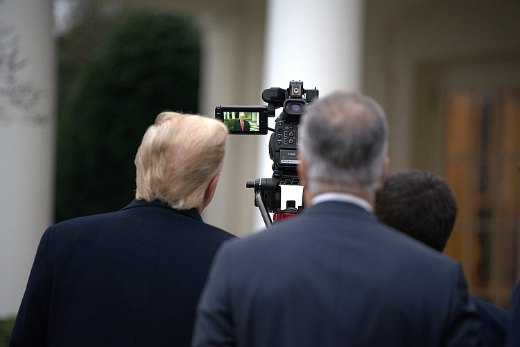 President Trump huddles with aides, watching a completed take of a video through the monitor of the video camera.