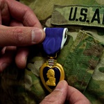 Image of the Purple Heart Medal and hand. Source: U.S. Army.
